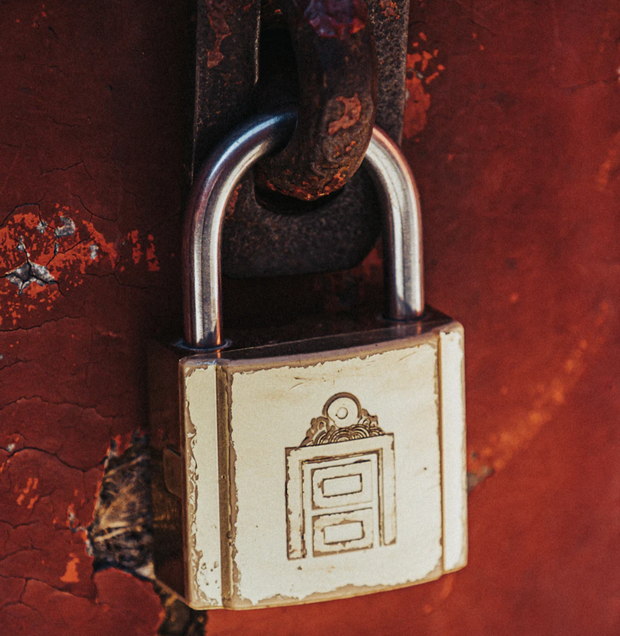 a padlock attached to a rusted red wall